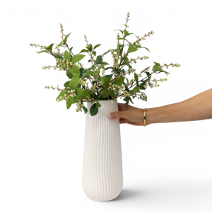 Hand holding the Short Zahra Ribbed White Vase with green foliage and pale buds to show its scale